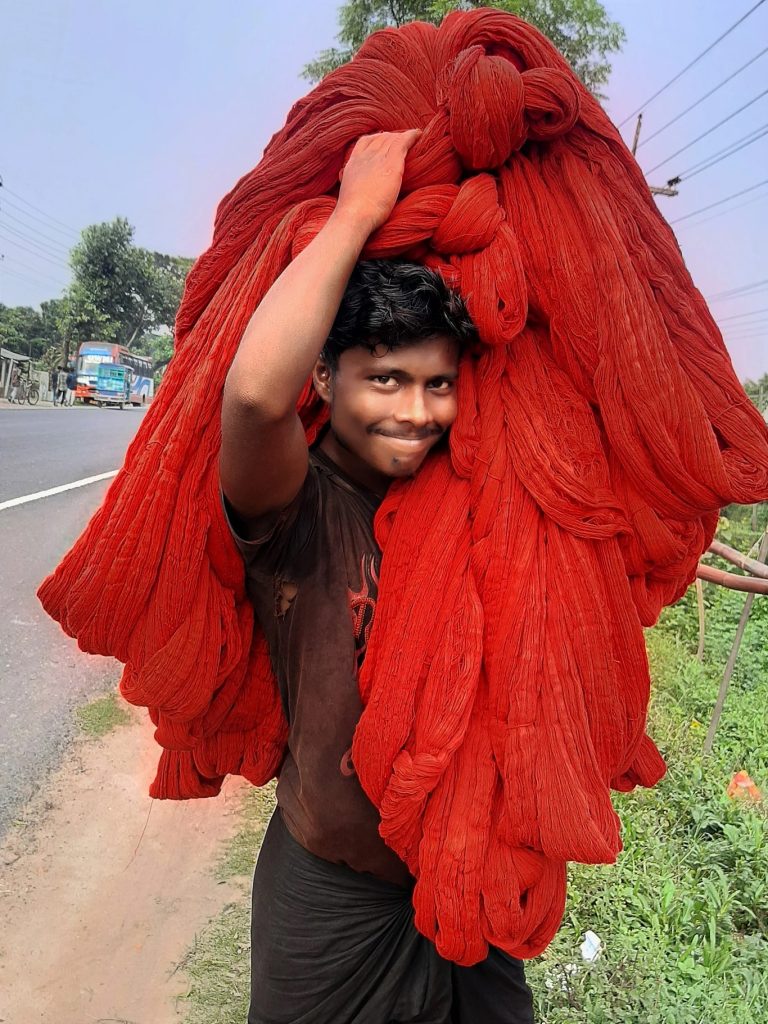রোদে শুকানোর পর সুতা ঘরে নিয়ে যাচ্ছেন শ্রমিক।